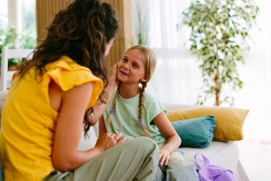 Mother and daughter smiling together as they spend a warm family moment in the living room