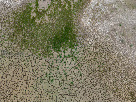 Aerial view of the dry, cracked earth and patches of green vegetation at the Tagebau Hambach open-pit mine in Elsdorf, Nordrhein-Westfalen, Germany.