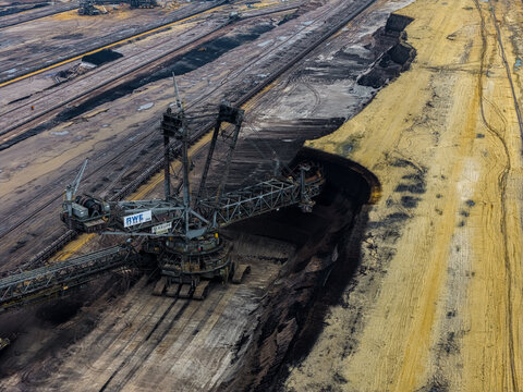 Aerial view of the massive bucket-wheel excavator at the Garzweiler surface mine, showcasing deep excavation layers and industrial landscape in Juchen, North Rhine-Westphalia, Germany.