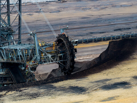 Aerial view of the massive bucket-wheel excavator operating at the Garzweiler surface mine, extracting coal from the deep earth in Juchen, North Rhine-Westphalia, Germany.
