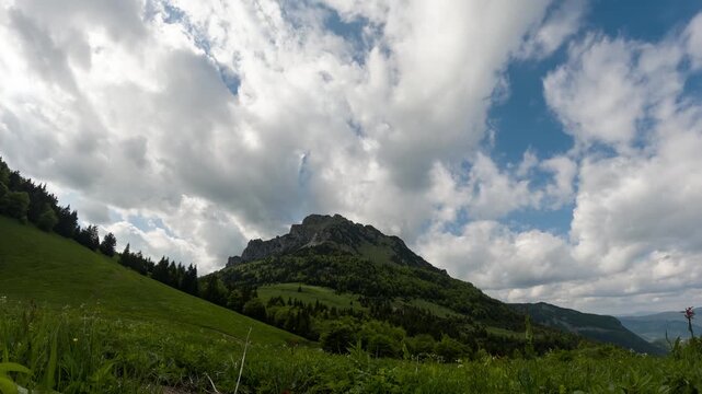 Timelapse of White Clouds Passing Over Green Mountain Peak and Meadow