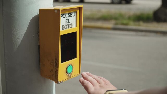 Traffic light activation button at pedestrian crossing pressed by caucasian woman hand. Road safety infrastructure in sunny spanish city and timer activation.