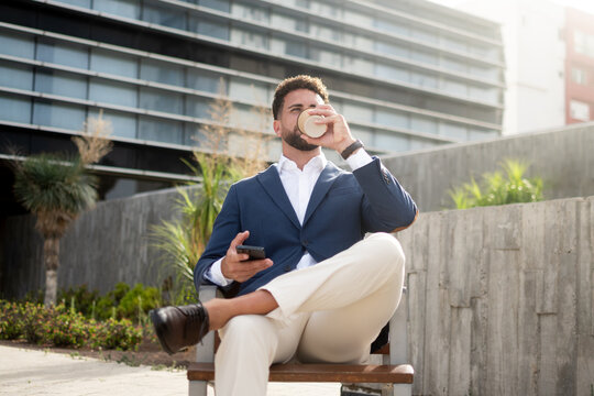 Businessman drinking takeaway coffee outside modern office