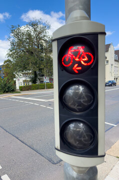 Modern bicycle traffic light showing red on a city street.