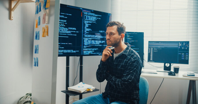 Young Caucasian male programmer write creative plan on whiteboard and coding on computer in home office workspace. AI technology, cybersecurity network, agile strategy, business innovation concept.