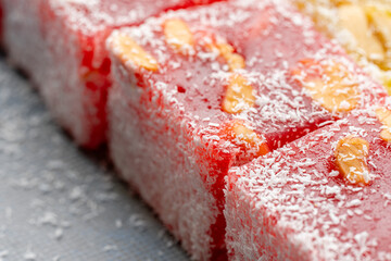Fototapeta premium Assorted Turkish delight sweets pattern background. Colorful Rahat lokum with nuts and coconut flakes close up. Dessert