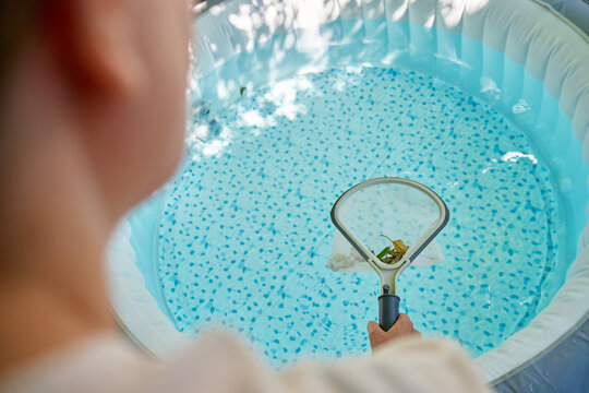 Person cleaning swimming pool with skimmer net
