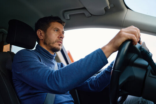 Focused man driving a car wearing a seatbelt