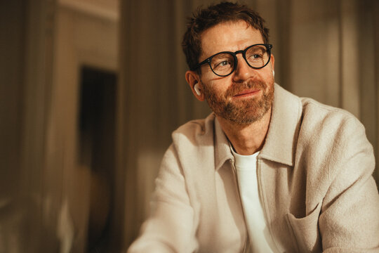 Businessman sits for a work portrait with glasses and earbuds