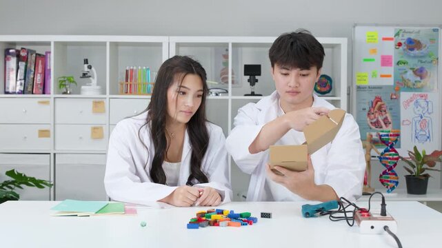 Teenage Students in Lab Coats Conducting Science Experiment with Cardboard Box