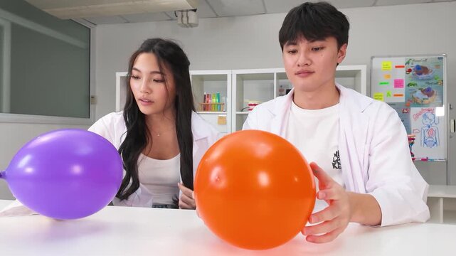Asian Teenage Students in Lab Coats Conducting Science Experiment with Balloons