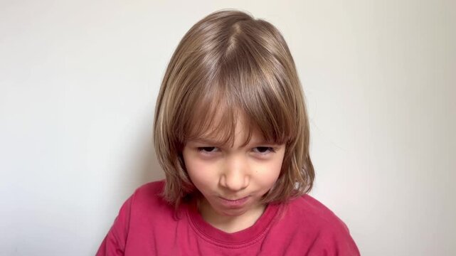 Little boy exhibiting an angry and grumpy facial expression indoors, mental health, family counseling, upset mood, childhood emotions