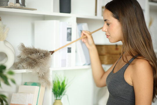 Woman at home cleaning furniture with duster