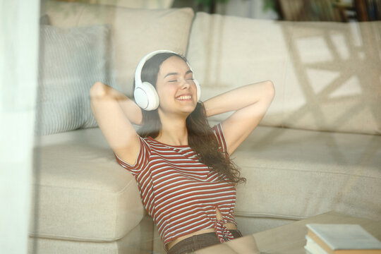 Happy teenage girl wearing headphone relaxing listening audio