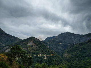 Obraz premium Majestic green mountain range under a dramatic heavy cloudy sky captured in high resolution showcasing the raw natural beauty of rugged peaks and deep forested valleys