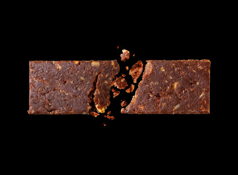 Broken chocolate cereal energy bar in the air close-up isolated on a black background