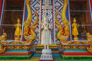 Fototapeta premium White standing angel statue flanked by golden Buddha figures and Naga serpents at Wat Sri Uthumphon in Mueang Nakhon Sawan District, Nakhon Sawan, Thailand, showcasing ornate Thai art facade.