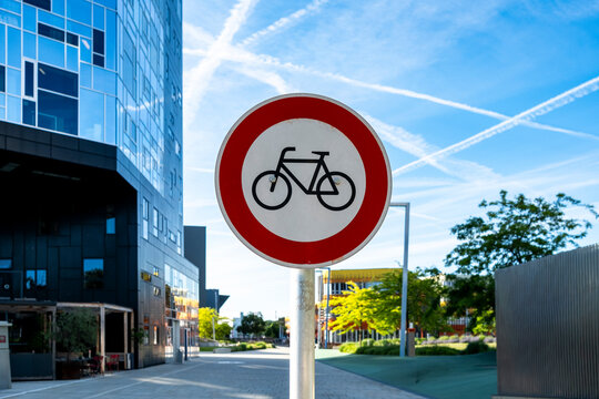 Bicycle traffic sign in Vienna, Austria, set against a modern urban streetscape with contemporary buildings, blue sky and roadside greenery