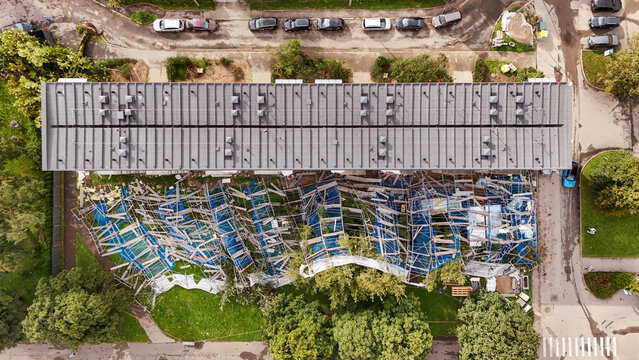 Riga, Latvia - 23 August 2026: Aerial view of a residential building with collapsed scaffolding and blue protective netting at a construction site.