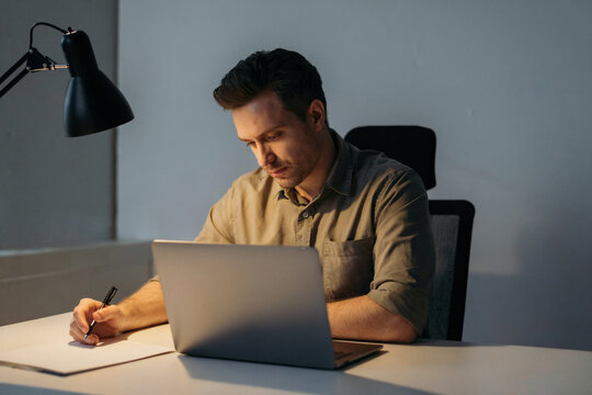 Thoughtful professional working at a desk in a dimly lit office