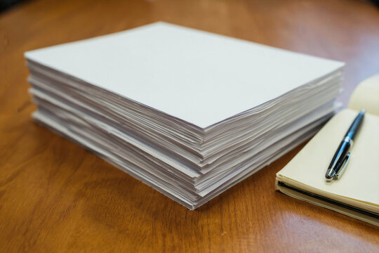 Stack of Blank White Paper and Notebook on Wooden Table