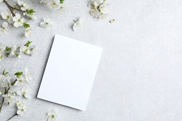 Top view of cherry blossoms and white paper card, spring flower background, flat lay, copy space © Sunlight