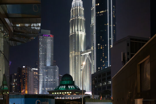 Night view of the Petronas Twin Towers, KL Tower, and city skyline framed by the modern glass facade of Ombak KLCC on August 23, 2026 in Kuala Lumpur, Malaysia.
