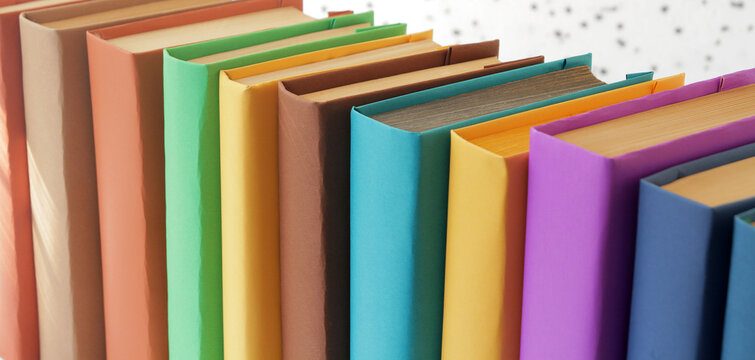 Colorful books with multicolored covers arranged in a row on a table, featuring various complementary color combinations. Books as a symbol of learning and education.