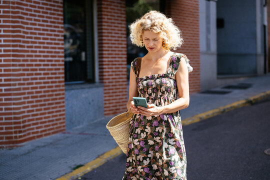 Middle Aged Blonde Woman Using Smartphone Outdoors on Sunny European City Street