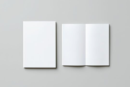 Blank white tri-fold brochure and closed booklet on grey surface