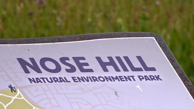 Extreme close-up of a Nose Hill Natural Environment Park sign with grassy background in Calgary, Alberta, Canada.
