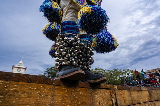 View of a traditional Kurpites dancer wearing ornate leg bells and colorful tassels while performing on a wooden stage in Nuevo San Juan Parangaricutiro, Michoacan, Mexico.