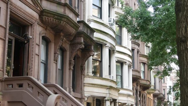 New York City townhouse buildings, brownstone row houses in Manhattan or Brooklyn, United States of America. Classic buildings on residential district street. Real estate property. Rowhouse townhome.