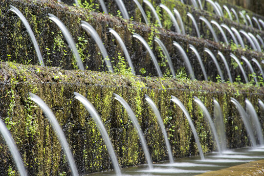View of the cascading water features at Parque Nacional Barranca del Cupatitzio with moss-covered stone walls and flowing water streams in Uruapan, Michoacan, Mexico.