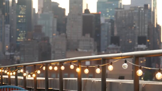 New York City Manhattan Midtown skyline from Queens, United States. Skyscraper buildings architecture, cityscape from rooftop in Long Island, Hunters Point. Light bulbs garland on roof, urban sunset.