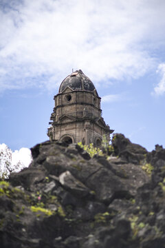 View of the stone bell tower of the San Juan Parangaricutiro church rising above solidified volcanic lava flows in Angahuan, Michoacan, Mexico.