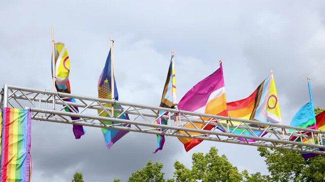 Rainbow and progress pride flags wave wind Magdeburg overcast sky background at CSD Pride 2026. Colorful banners symbolize diversity, equality, inclusion, freedom and LGBTQ community celebration