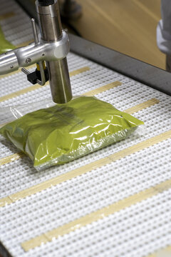 View of an automated packaging machine sealing a plastic pouch of guacamole on a conveyor belt at an avocado processing plant in Uruapan, Michoacan, Mexico.