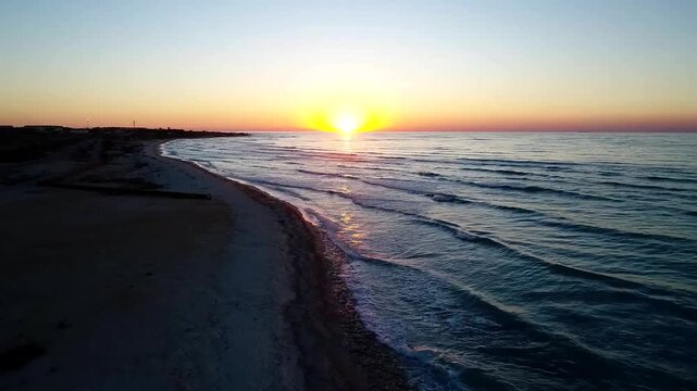 Aerial shot of Kish Island beach at sunset with golden light reflecting on calm sea water.