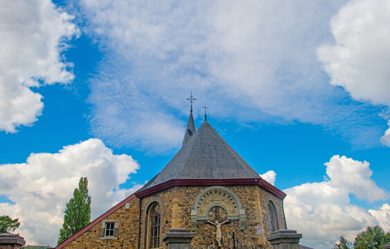Trees and an old church in sunlight and shadow in green woodland in summer, Voeren, Limburg, Belgium, August, 2026