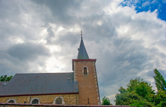 Trees and an old church in sunlight and shadow in green woodland in summer, Voeren, Limburg, Belgium, August, 2026