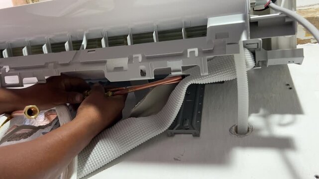 Technician cutting copper pipe with tube cutter during AC installation