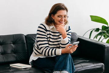 Communication shapes how the woman works from home on a couch with a smartphone