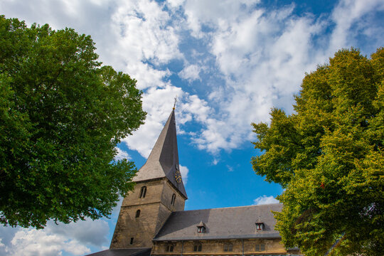 Trees and an old church in sunlight and shadow in green woodland in summer, Voeren, Limburg, Belgium, August, 2026