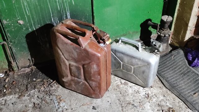 Vintage brown and silver fuel canisters standing near car parts in a garage