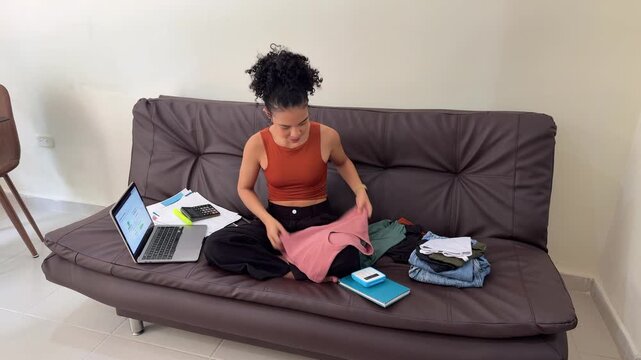 Young female entrepreneur managing online clothing store from home