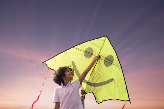 Happy little boy holding a kite and trying to fly