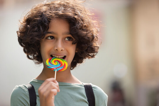 Portrait of a child boy licking a colourful big lollipop