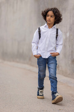 Little boy in school uniform walking down the street to school
