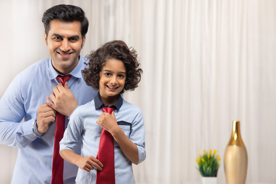 Father and son wearing ties together in front of mirror